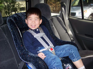 A smiling child sits in a child passenger safety seat