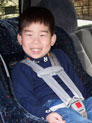 A smiling child sits in a child passenger safety seat