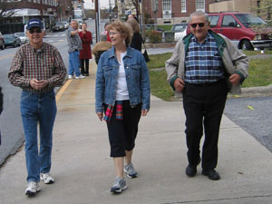 A group of senior pedestrians walking on a sidewalk