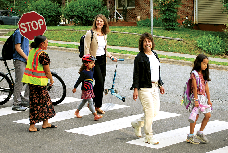 Lauren Marchetti walking with kids to school along a crosswalk.