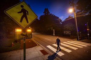 A man crossing the street at a crosswalk at night.