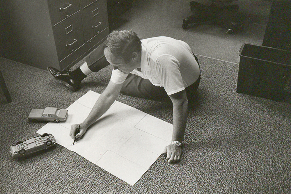 B.J. Campbell sits on the floor of his office, drawing an intersection.